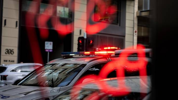 Emergency vehicles with flashing red lights on Australian street, building numbered 305