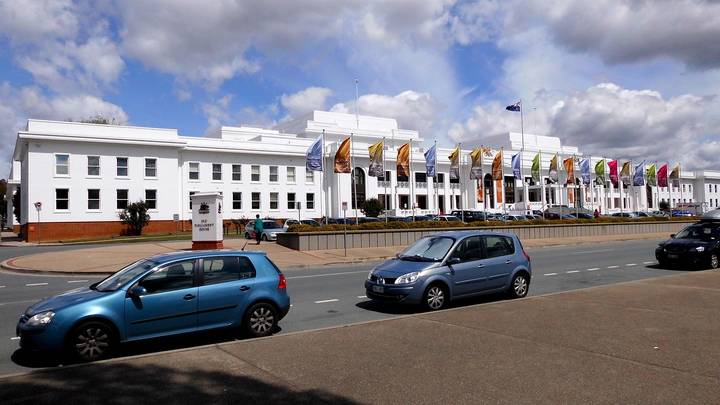 White Parliament House building with flags, Australian government building exterior