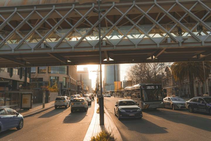 File image: City street under lattice overpass with buses and cars at sunset