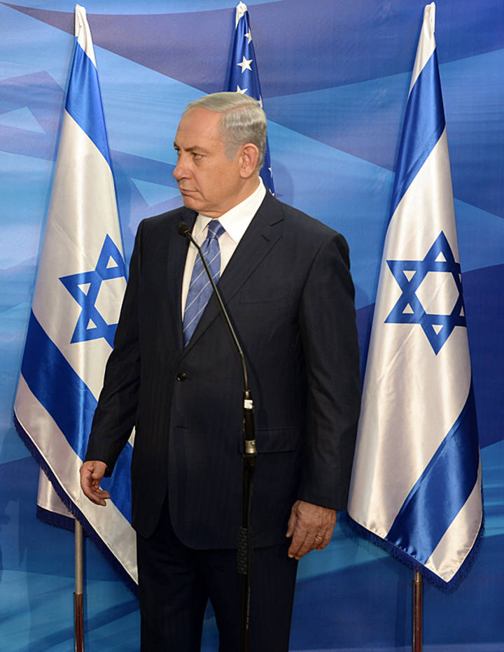 File image: Man in dark suit speaking at podium with Israeli flags behind him.