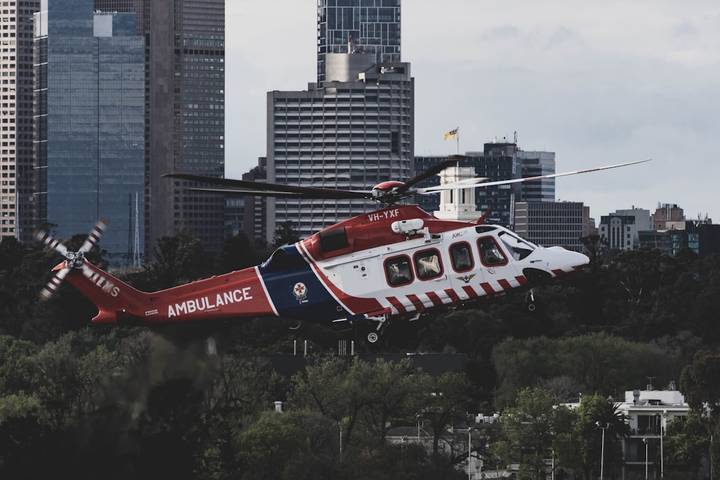 File image: Red and white ambulance helicopter in flight over cityscape.