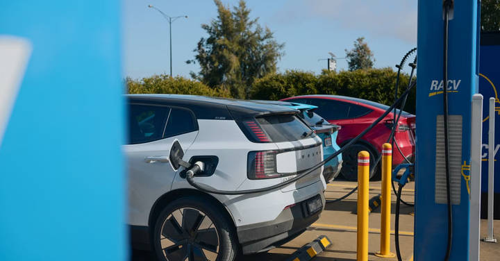 White and red electric vehicles charging at a modern station with infrastructure visible