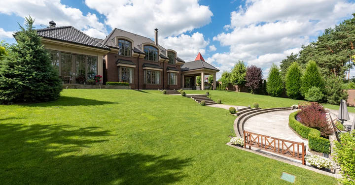 Large brick mansion with extensive manicured lawn and curved driveway