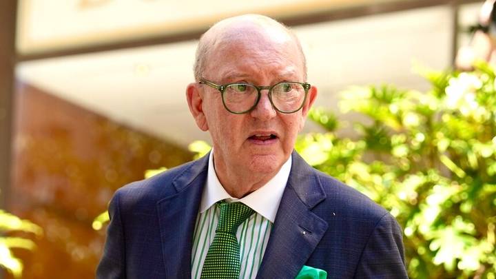 David Allan. Older man in glasses and suit speaking at formal indoor setting