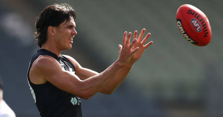 Elijah Hollands. Athlete on grass field wearing black sleeveless team shirt, gesturing in profile