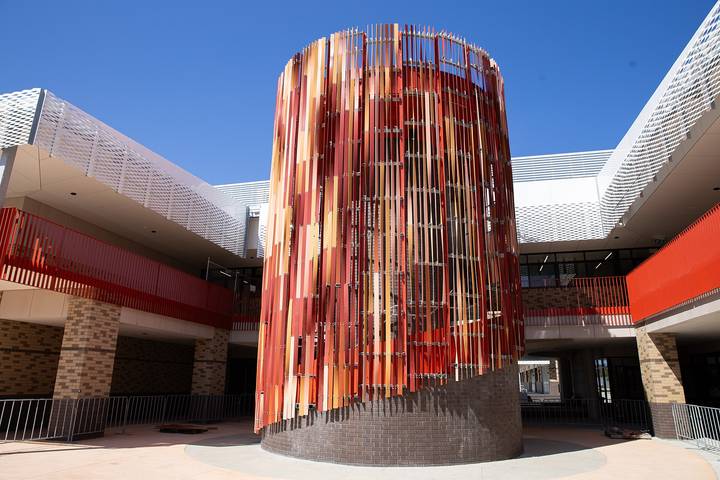 File image: Modern school building with red cylindrical tower and curved white roof sections under clear blue sky
