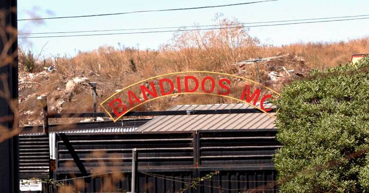 Bandidos MC clubhouse sign and metal-roofed building exterior with bare trees behind