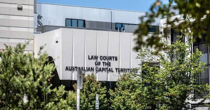 Modern law courts building facade with Australian Capital Territory signage, vegetation in foreground