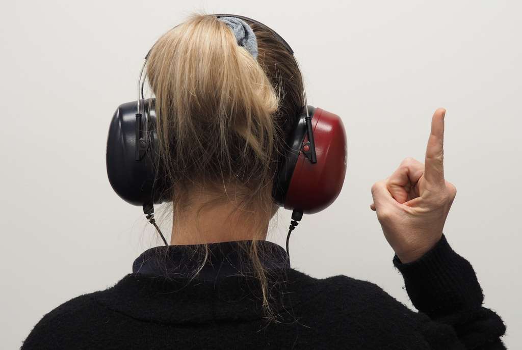 A woman wearing ear muffs with her finger up.