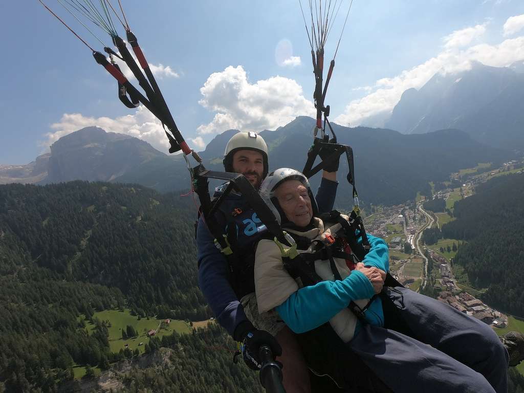 A man and woman soaring through the mountains while paragliding, protected by comprehensive Parachuting Insurance coverage.