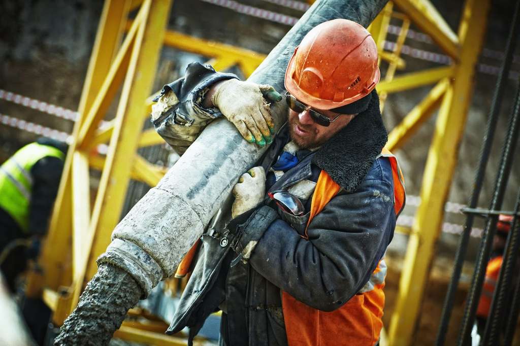 A construction worker holding a pipe on a construction site, protected by Contractors Protective Liability Insurance.