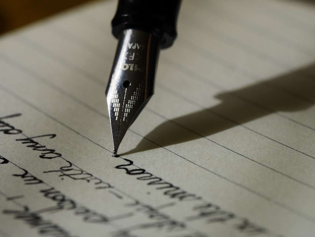 A translator is using a fountain pen to write on a piece of paper. A translator is using a fountain pen to write on a piece of paper.