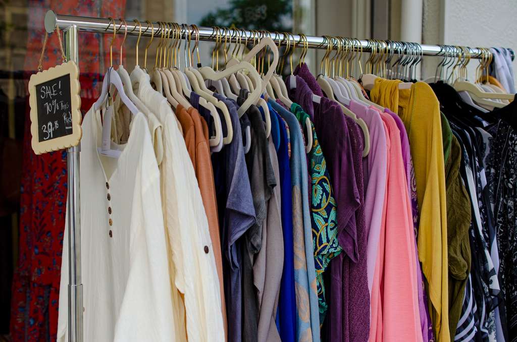 A rack of clothes with a sign on it at a thrift store.