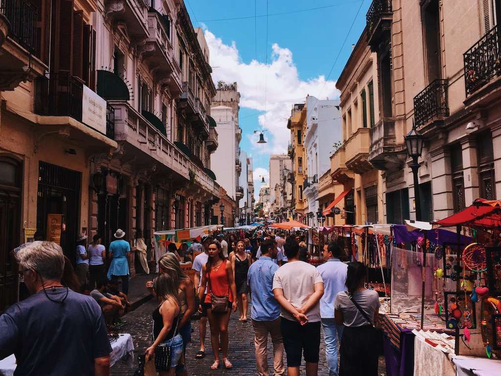 A street fair in Havana, with a lively crowd of people walking down the street.