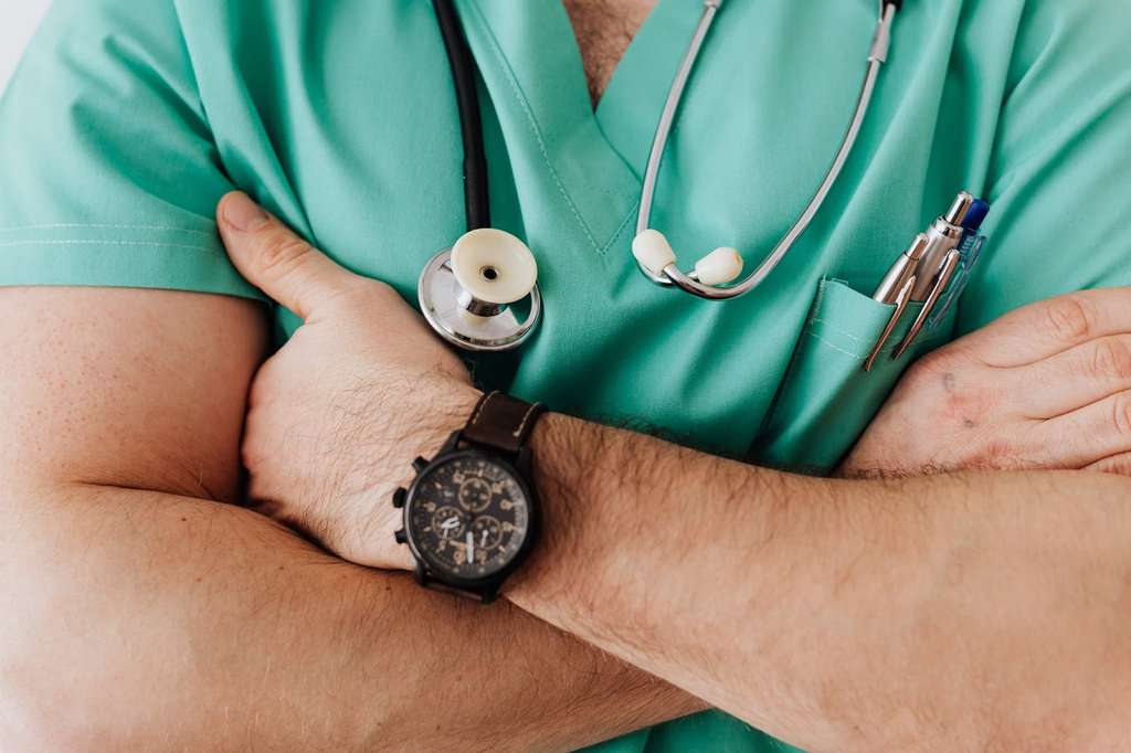 A male sonographer with his arms crossed and a watch on his wrist.