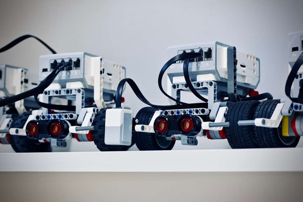 A few robotics robots are lined up on a shelf.