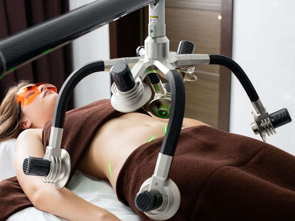 A woman laying on a bed at a weight loss clinic with a machine attached to her.