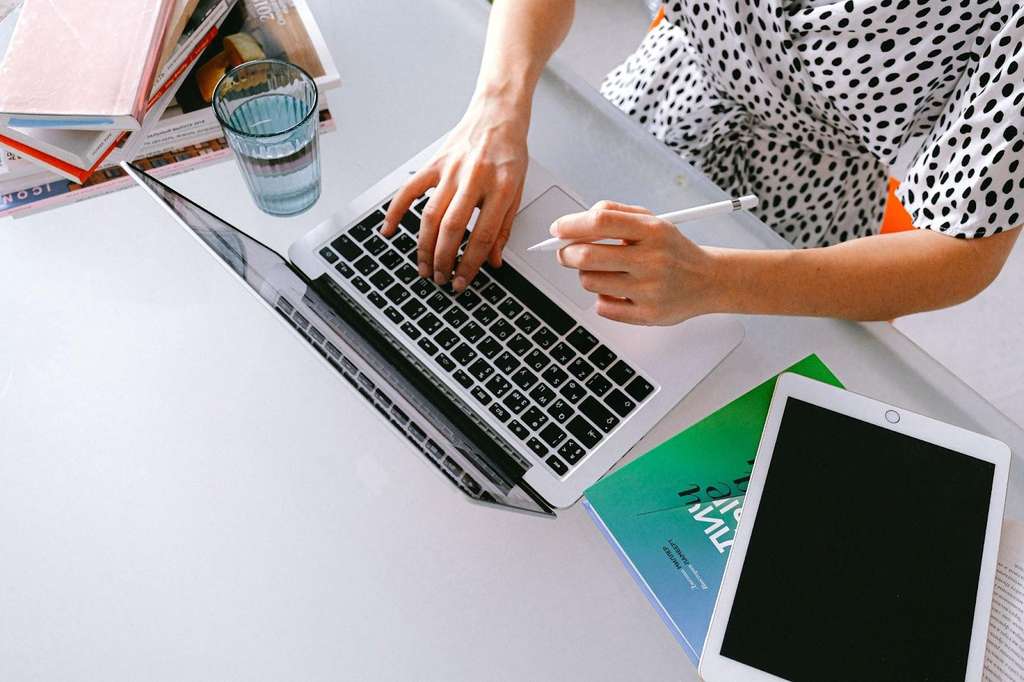 A woman working from home, typing on a laptop at a desk.