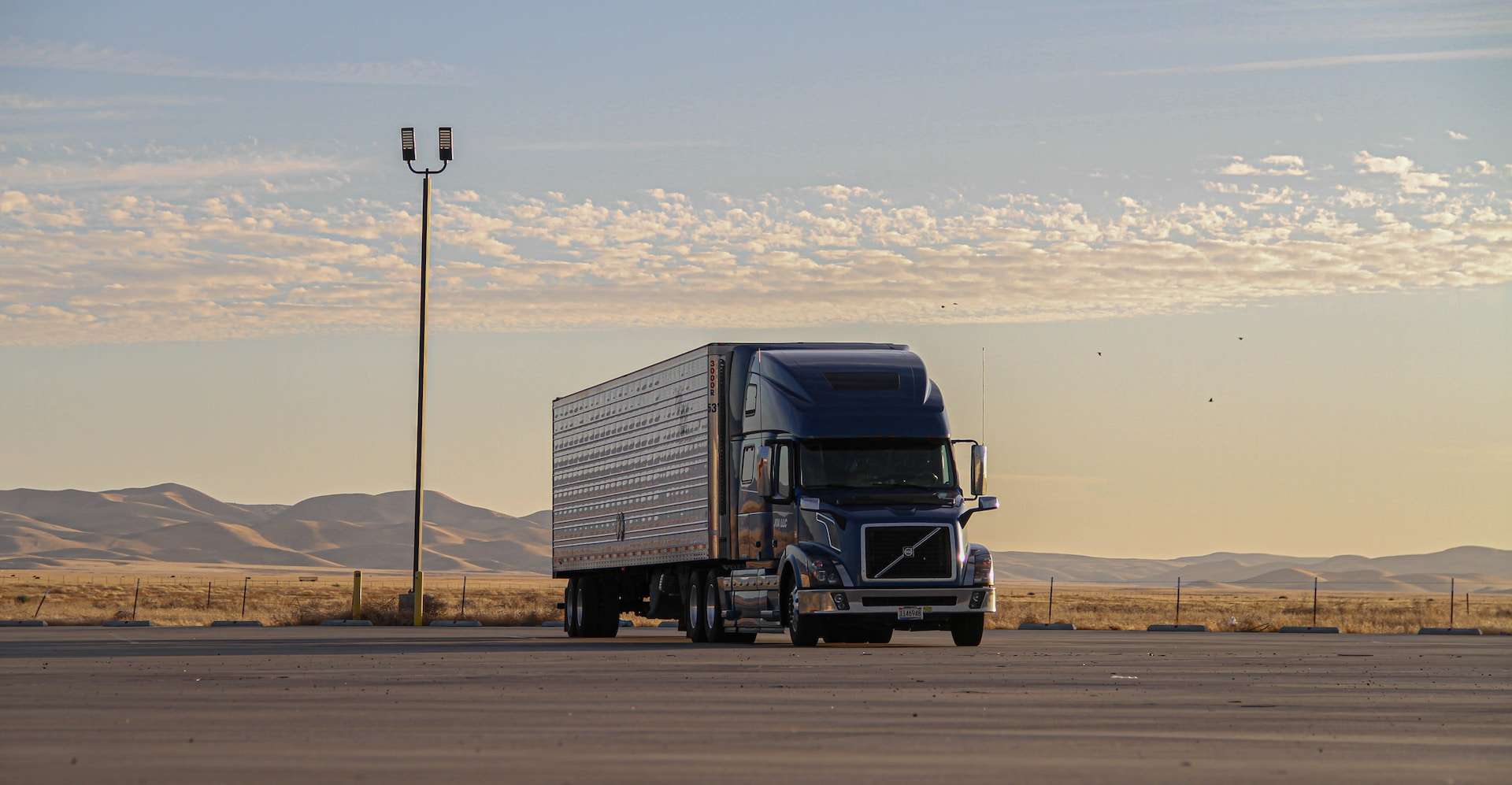 An enormous semi truck roaring across the barren desert.