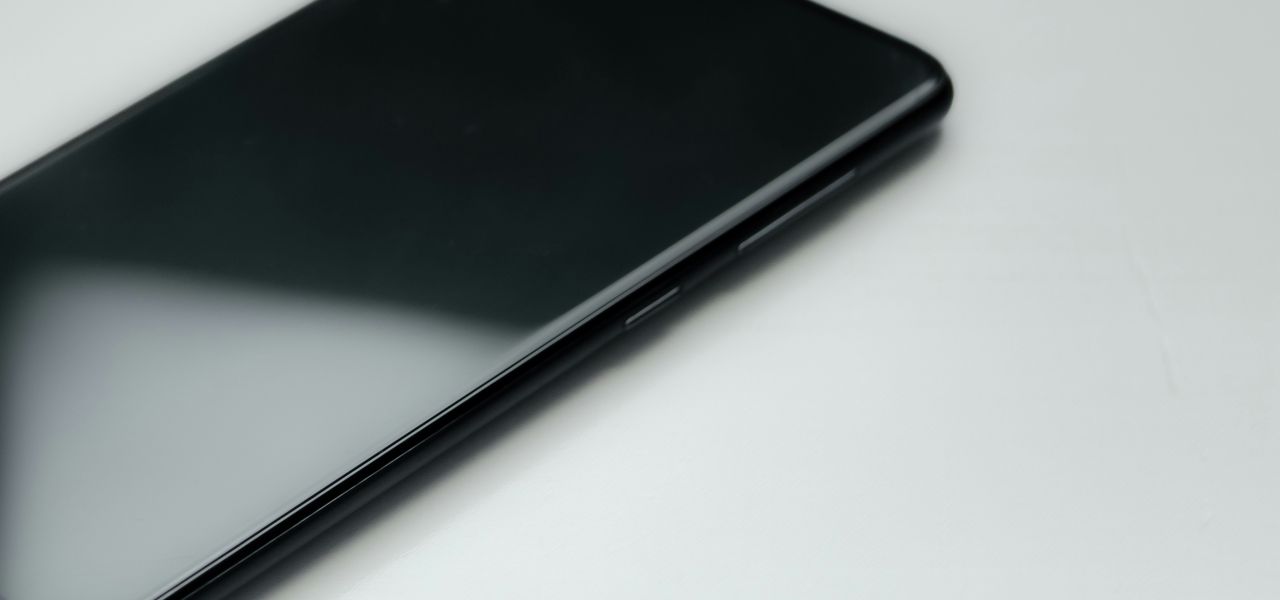 a black cell phone sitting on top of a white table