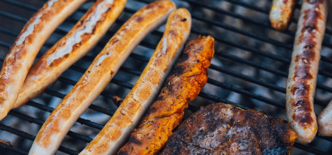 a grill with several sausages and hot dogs cooking on it
