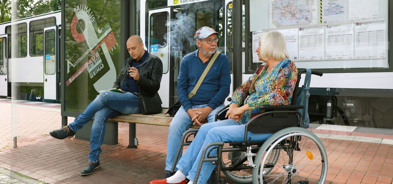 a group of people sitting on a bench next to a bus