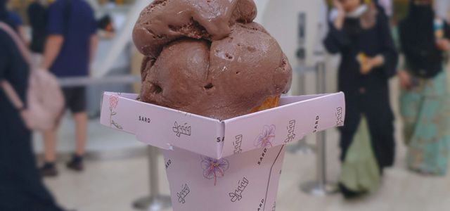 a hand holding up a chocolate ice cream cone