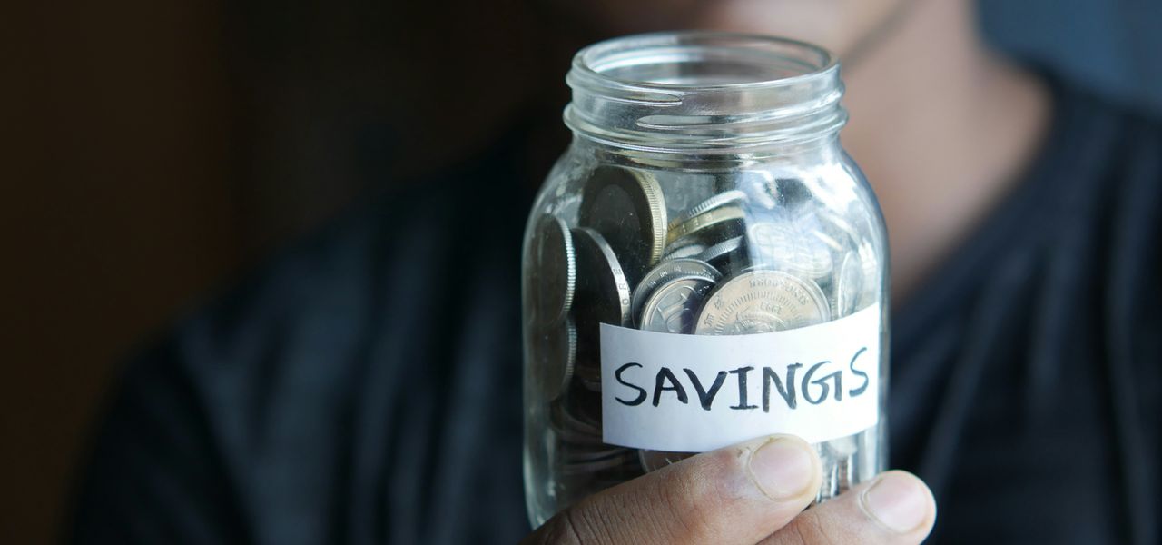 a man holding a jar with a savings label on it