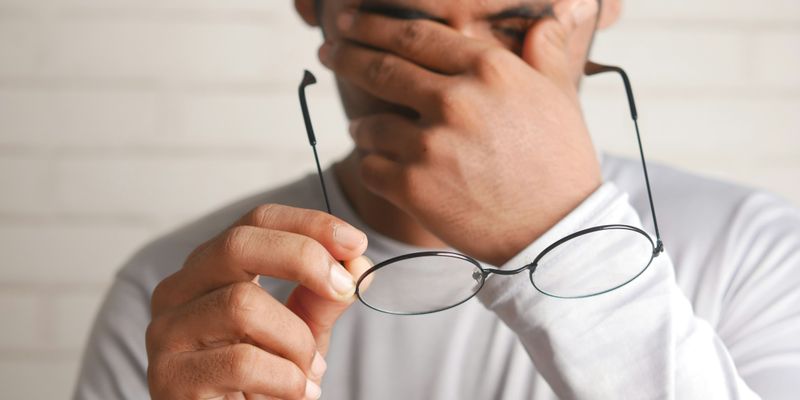 a man holding a pair of glasses up to his face