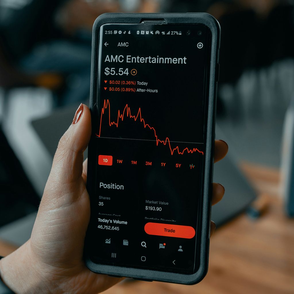 a person holding a cell phone with an amg entertainment app on the screen