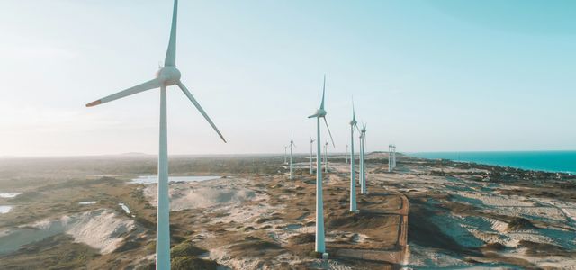 a row of wind turbines next to the ocean