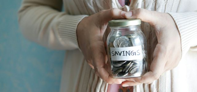 a woman holding a jar with savings written on it