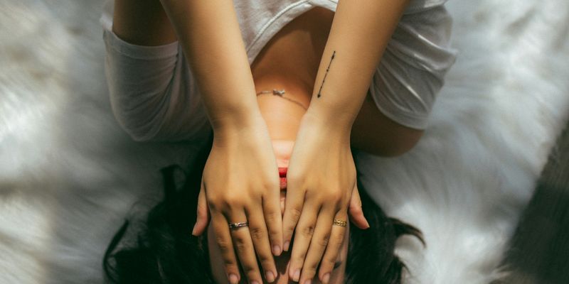 a woman holds her hands over her face