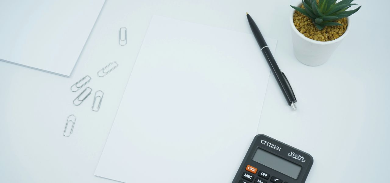 black calculator beside black pen on white printer paper