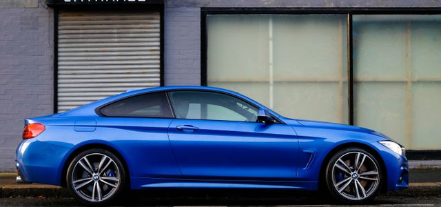 blue coupe beside gray house