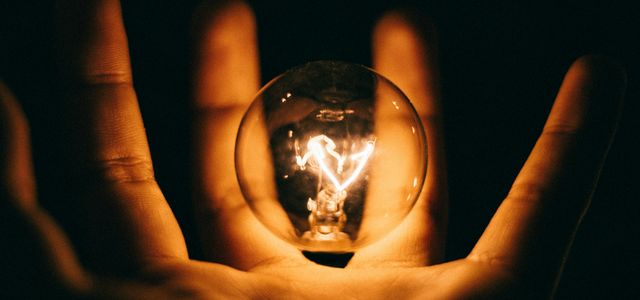 clear glass bulb on human palm