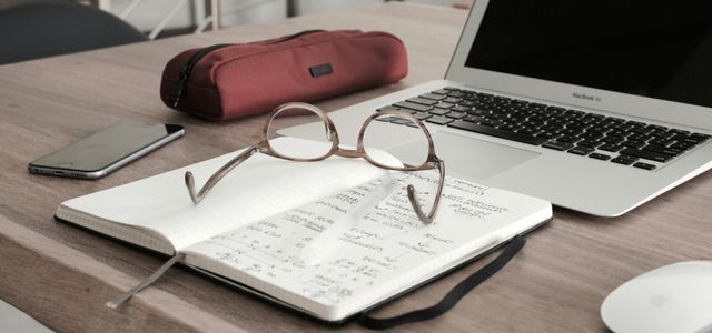 eyeglasses on book beside laptop