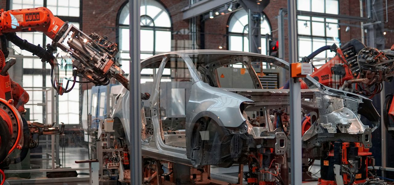 gray vehicle being fixed inside factory using robot machines