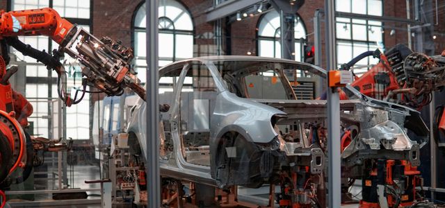 gray vehicle being fixed inside factory using robot machines