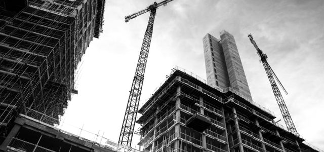 grayscale photo of crane in front of building