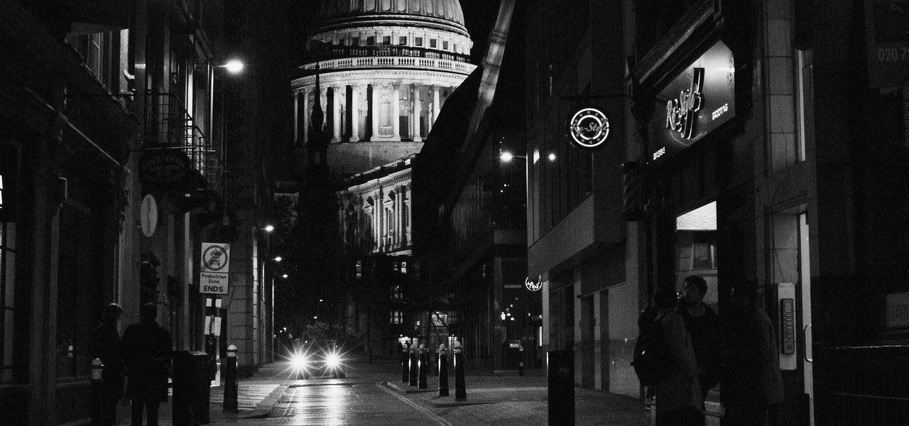 grayscale photo of empty road between buildings