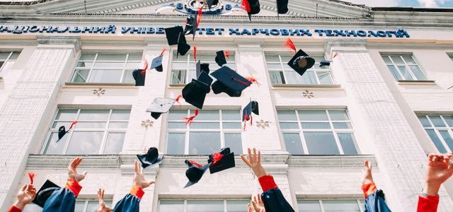 group of fresh graduates students throwing their academic hat in the air