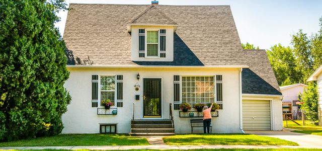man in black shirt sitting on chair near white wooden house during daytime