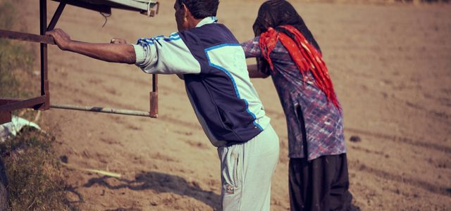 man in white dress shirt and brown pants holding brown wooden stick
