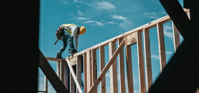 man in yellow shirt and blue denim jeans jumping on brown wooden railings under blue and