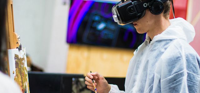 man wearing black virtual reality headset while painting near brown wall