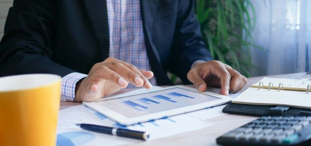 person in black suit jacket holding white tablet computer