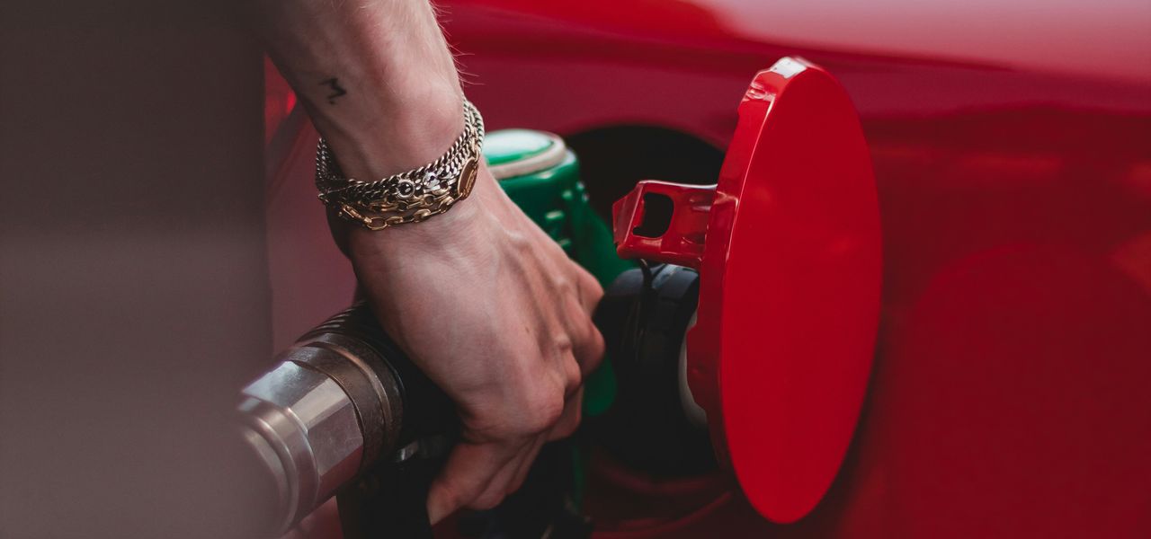 person in red shirt wearing silver bracelet holding red and black metal tool
