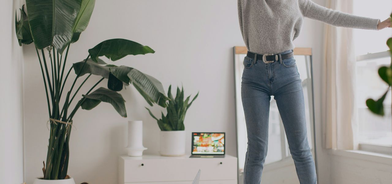 person in white long sleeve shirt and blue denim jeans standing on white bed