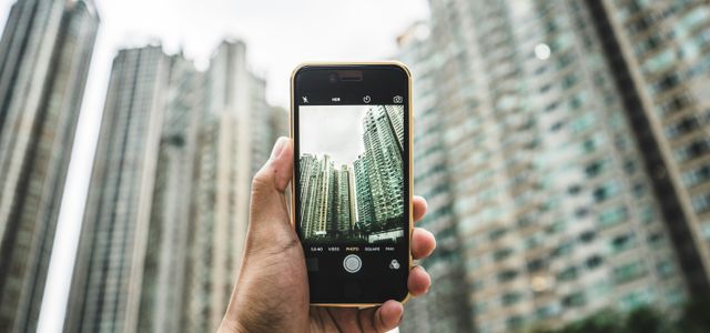 person using smartphone taking picture of building